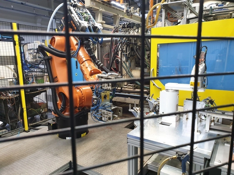 Ein oranger Kuka-Industrieroboter in einer automatisierten Fertigungszelle, dem Arbeitsumfeld von Michele Russo.